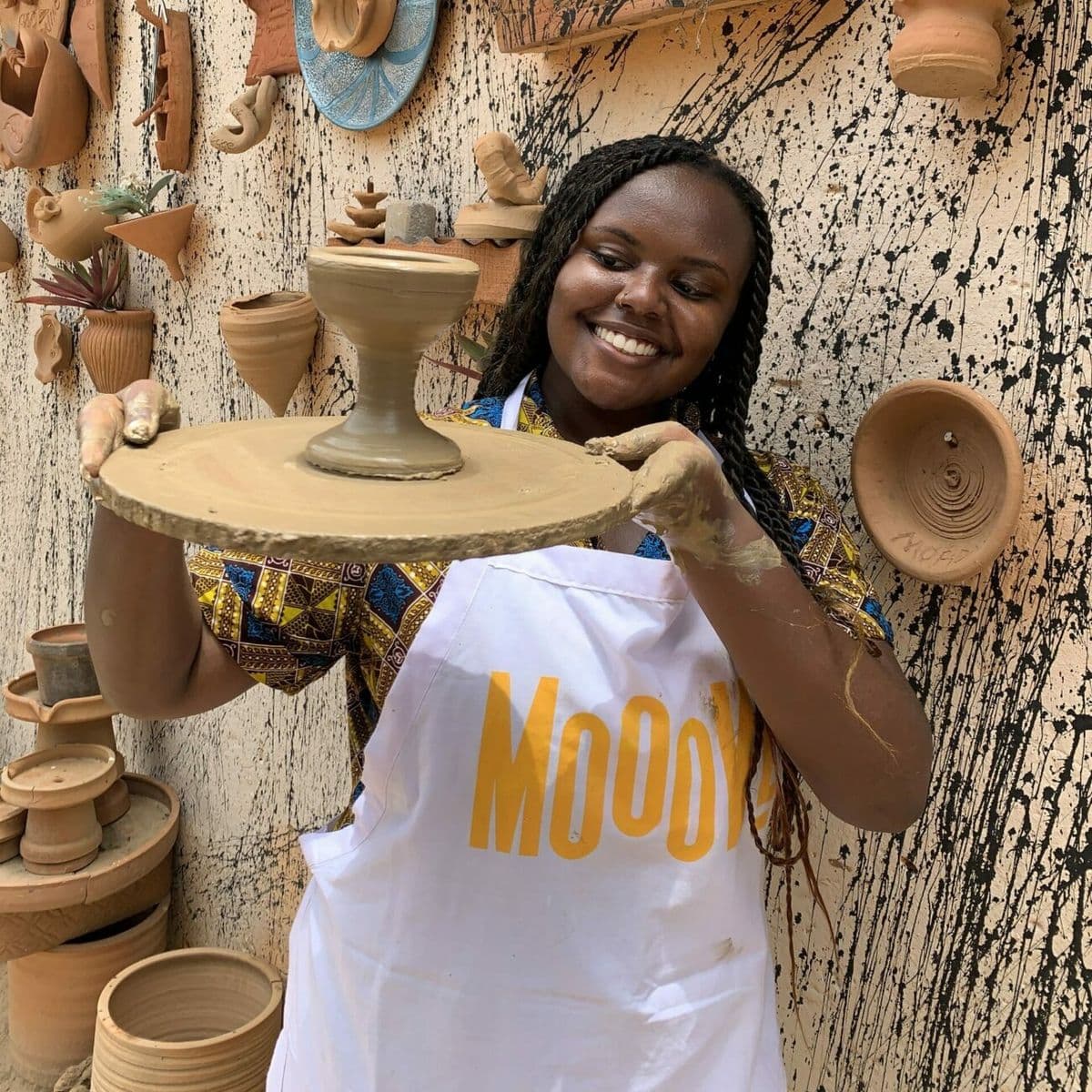 Woman holding finished pottery piece with pride